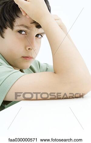 Boy frowning at camera, holding head, leaning on elbow View Large Photo Image Stock Image - Boy frowning at camera, holding head, leaning on elbow. Fotosearch
