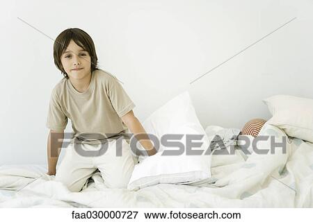 Boy kneeling on unmade bed, smiling at camera View Large Photo Image Stock Photo - Boy kneeling on unmade bed, smiling at camera. Fotosearch
