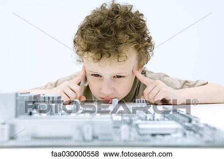 Boy looking at circuit board, holding fingers to his temples View Large Photo Image Stock Photo - Boy looking at circuit board, holding fingers to his temples. Fotosearch