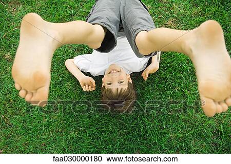 Boy lying on grass with legs in air, overhead view View Large Photo Image Stock Image - Boy lying on grass with legs in air, overhead view. Fotosearch