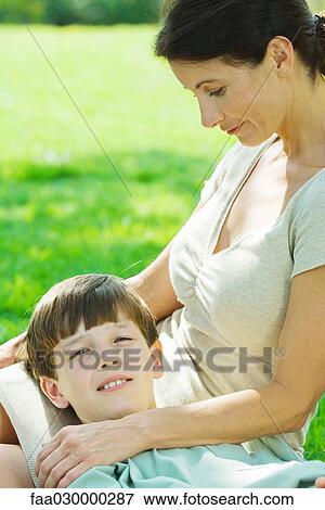 Boy lying with head in his mother's lap, smiling at camera View Large Photo Image Stock Photo - Boy lying with head in his mother's lap, smiling at camera. Fotosearch