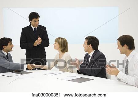 Business associates at conference table, two shaking hands, the others clapping View Large Photo Image Stock Image - Business associates at conference table, two shaking hands, the others clapping. Fotosearch