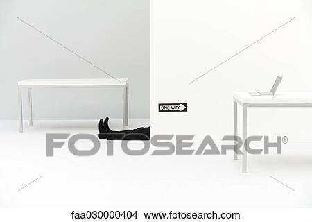 Businessman lying on the ground in office, "one way" sign pointing toward laptop computer on desk View Large Photo Image Picture - Businessman lying on the ground in office, "one way" sign pointing toward laptop computer on desk. Fotosearch