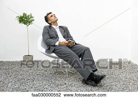 Businessman relaxing in rock garden, listening to mp3 player View Large Photo Image Stock Image - Businessman relaxing in rock garden, listening to mp3 player. Fotosearch