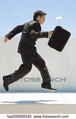 Businessman running in midair, holding briefcase with flower sticking out, side view View Large Photo Image Stock Image - Businessman running in midair, holding briefcase with flower sticking out, side view. Fotosearch