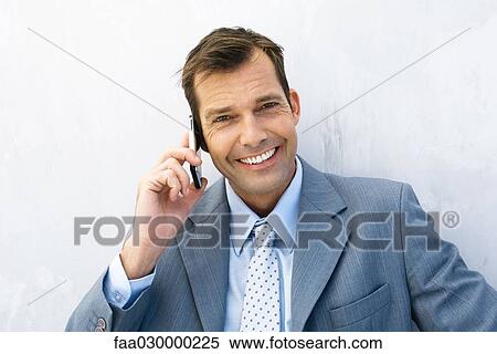 Businessman using cell phone, smiling at camera View Large Photo Image Stock Photography - Businessman using cell phone, smiling at camera. Fotosearch