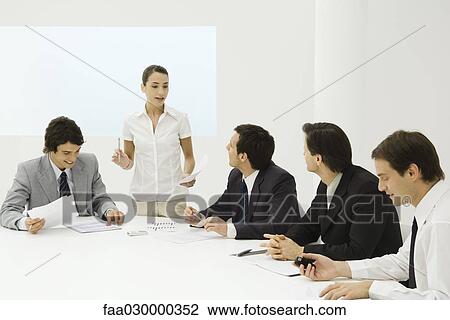 Businesswoman addressing male colleagues at conference table View Large Photo Image Stock Image - Businesswoman addressing male colleagues at conference table. Fotosearch