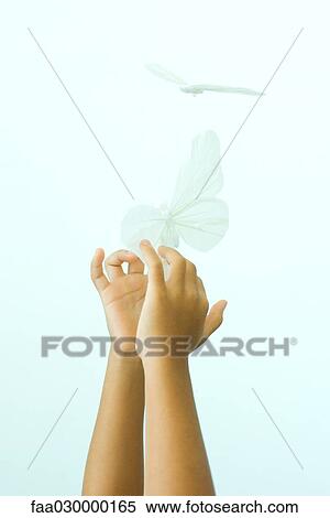 Stock Photography - Child reaching for fake butterfly, cropped view of arms. Fotosearch