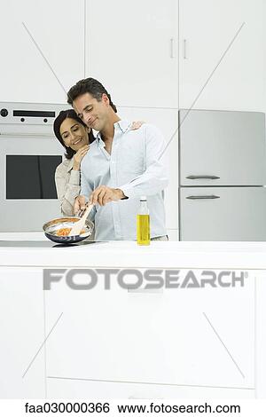 Couple cooking together in kitchen, smiling View Large Photo Image Stock Photograph - Couple cooking together in kitchen, smiling. Fotosearch