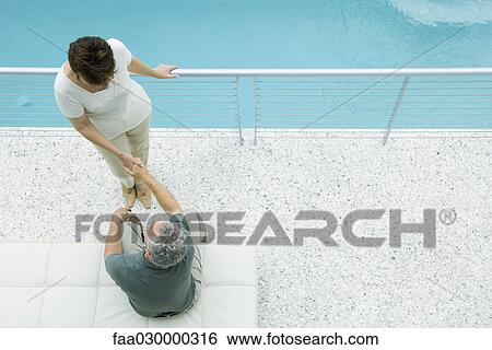 Couple on balcony, holding hands, high angle view View Large Photo Image Stock Photograph - Couple on balcony, holding hands, high angle view. Fotosearch