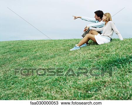 Couple sitting on grass, looking toward distance View Large Photo Image Stock Image - Couple sitting on grass, looking toward distance. Fotosearch