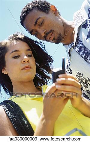 Couple using cell phone, low angle view View Large Photo Image Stock Photo - Couple using cell phone, low angle view. Fotosearch