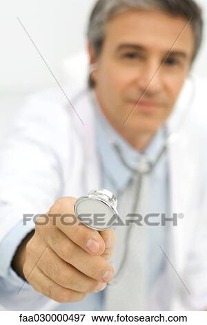 Doctor holding stethoscope toward camera, focus on foreground View Large Photo Image Stock Photo - Doctor holding stethoscope toward camera, focus on foreground. Fotosearch