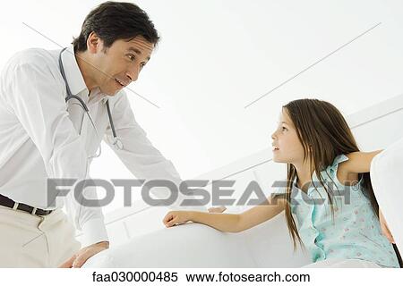 Stock Photography - Doctor leaning over, talking with little girl. Fotosearch