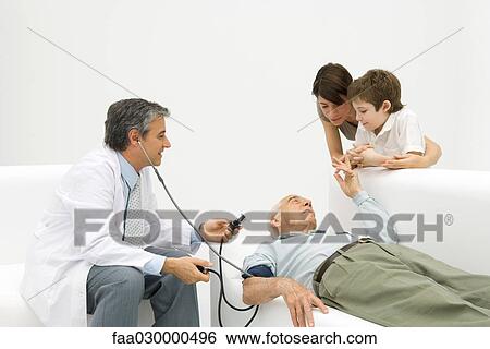 Stock Photograph - Doctor measuring elderly man's blood pressure, family watching. Fotosearch