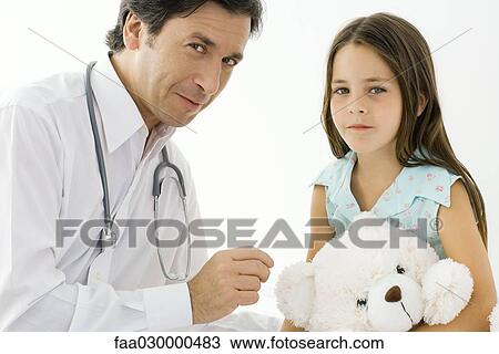 Doctor sitting with little girl, both smiling at camera View Large Photo Image Stock Image - Doctor sitting with little girl, both smiling at camera. Fotosearch