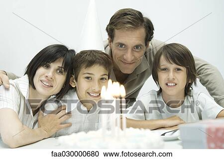 Family in front of birthday cake with lit candles, one boy wearing party hat View Large Photo Image Stock Image - Family in front of birthday cake with lit candles, one boy wearing party hat. Fotosearch