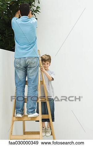 Father and son standing on ladder together, boy smiling at camera View Large Photo Image Stock Photo - Father and son standing on ladder together, boy smiling at camera. Fotosearch