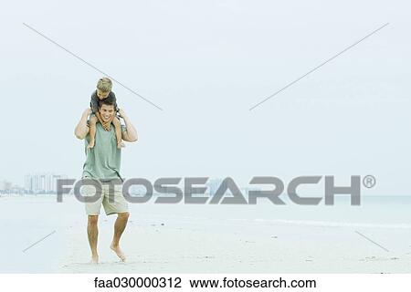 Father and son walking at the beach, man carrying boy on his shoulders View Large Photo Image Stock Image - Father and son walking at the beach, man carrying boy on his shoulders. Fotosearch