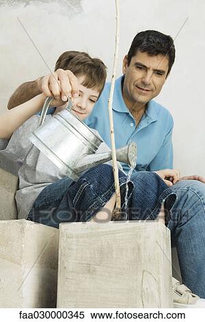Father and son watering potted plant together, both smiling View Large Photo Image Stock Photography - Father and son watering potted plant together, both smiling. Fotosearch