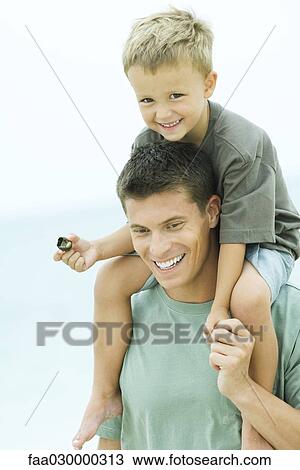 Father carrying son on shoulders, boy looking at camera, both smiling View Large Photo Image Stock Image - Father carrying son on shoulders, boy looking at camera, both smiling. Fotosearch