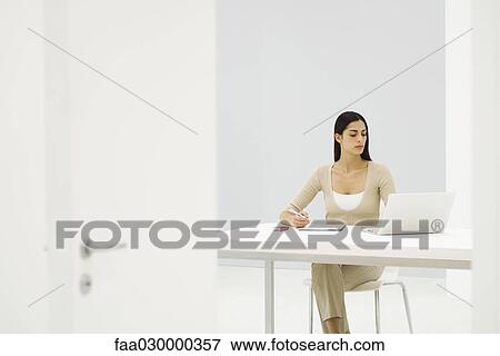 Female office worker sitting at desk, using laptop computer View Large Photo Image Stock Photo - Female office worker sitting at desk, using laptop computer. Fotosearch