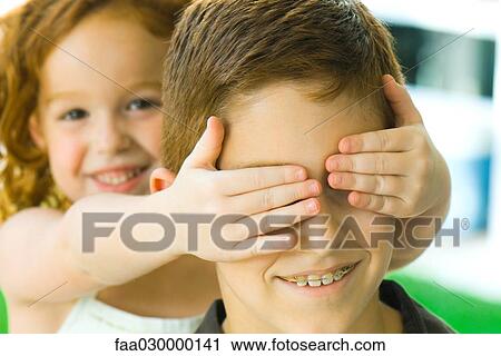 Girl holding hands over big brother's eyes, close-up View Large Photo Image Stock Image - Girl holding hands over big brother's eyes, close-up. Fotosearch