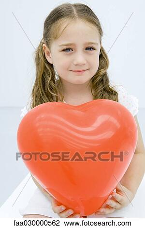 Girl holding large balloon heart, smiling at camera, portrait View Large Photo Image Stock Image - Girl holding large balloon heart, smiling at camera, portrait. Fotosearch