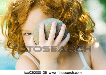 Girl holding up stone to face View Large Photo Image Stock Photograph - Girl holding up stone to face. Fotosearch