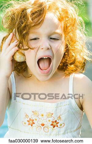 Girl listening to seashell, shouting View Large Photo Image Stock Photo - Girl listening to seashell, shouting. Fotosearch