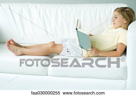 Girl lying on sofa, reading book View Large Photo Image Stock Photography - Girl lying on sofa, reading book. Fotosearch