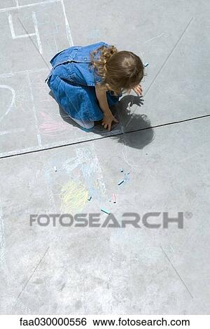 Stock Photograph - Girl playing with chalk, hunched over, high angle view. Fotosearch