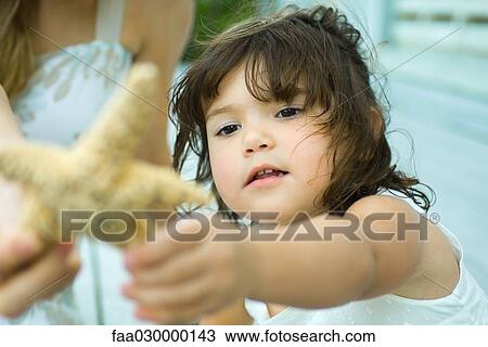 Girl reaching for starfish View Large Photo Image Stock Image - Girl reaching for starfish. Fotosearch