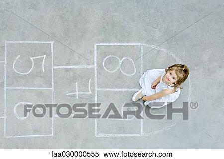 Stock Photography - Girl sitting down on hopscotch grid, looking up, overhead view. Fotosearch
