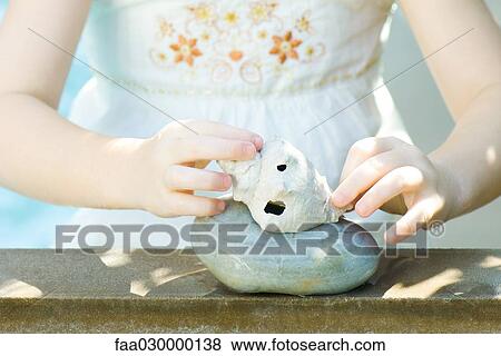 Stock Photo - Girl stacking seashell on stone. Fotosearch