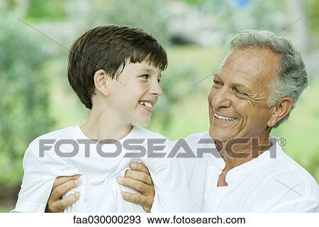 Grandfather and grandson smiling at each other, man holding boy View Large Photo Image Stock Image - Grandfather and grandson smiling at each other, man holding boy. Fotosearch