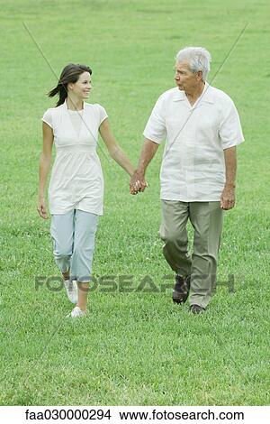 Grandfather and teen granddaughter walking outdoors, holding hands, smiling at each other View Large Photo Image Picture - Grandfather and teen granddaughter walking outdoors, holding hands, smiling at each other. Fotosearch