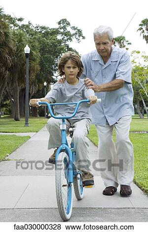 Grandfather teaching boy to ride bicycle, full length View Large Photo Image Stock Photo - Grandfather teaching boy to ride bicycle, full length. Fotosearch