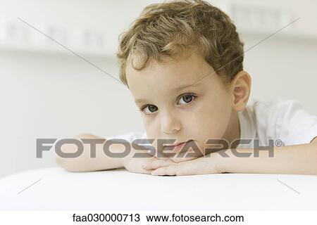 Little boy looking at camera, head resting on arms, portrait View Large Photo Image Stock Image - Little boy looking at camera, head resting on arms, portrait. Fotosearch