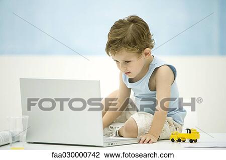 Little boy looking at laptop computer View Large Photo Image Stock Image - Little boy looking at laptop computer. Fotosearch