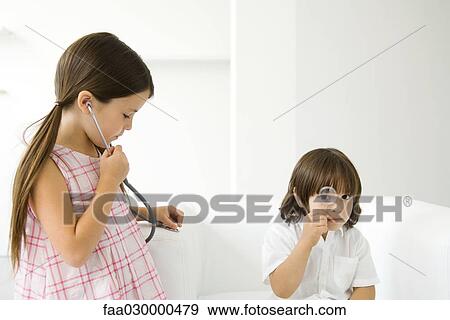 Little boy looking through magnifying glass at camera, girl listening to stethoscope View Large Photo Image Stock Photo - Little boy looking through magnifying glass at camera, girl listening to stethoscope. Fotosearch