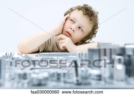 Stock Image - Little boy next to circuit board, holding head, looking up. Fotosearch