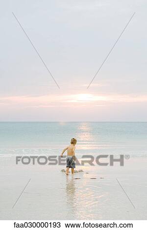 Little boy playing on beach at sunset, rear view, full length View Large Photo Image Stock Image - Little boy playing on beach at sunset, rear view, full length. Fotosearch