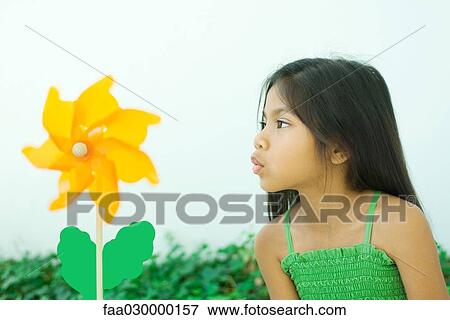 Stock Photo - Little girl blowing pinwheel flower. Fotosearch