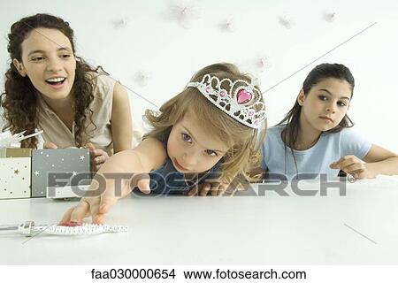 Little girl dressed as princess, reaching for wand, mother and sister watching View Large Photo Image Picture - Little girl dressed as princess, reaching for wand, mother and sister watching. Fotosearch