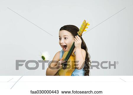 Little girl playing guitar, making face as flower leans toward her View Large Photo Image Stock Image - Little girl playing guitar, making face as flower leans toward her. Fotosearch
