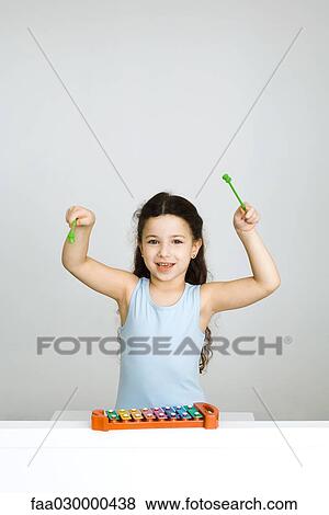 Little girl playing xylophone, arms raised, looking at camera View Large Photo Image Stock Photo - Little girl playing xylophone, arms raised, looking at camera. Fotosearch