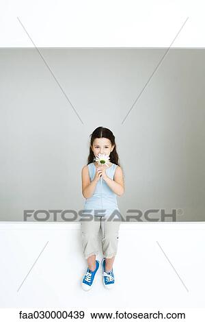 Little girl sitting on ledge, smelling flower, full length View Large Photo Image Stock Photo - Little girl sitting on ledge, smelling flower, full length. Fotosearch