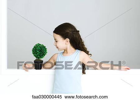 Little girl standing with arm around potted plant View Large Photo Image Stock Photography - Little girl standing with arm around potted plant. Fotosearch