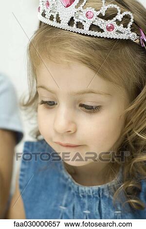 Little girl wearing toy tiara, looking down, close-up View Large Photo Image Stock Photo - Little girl wearing toy tiara, looking down, close-up. Fotosearch
